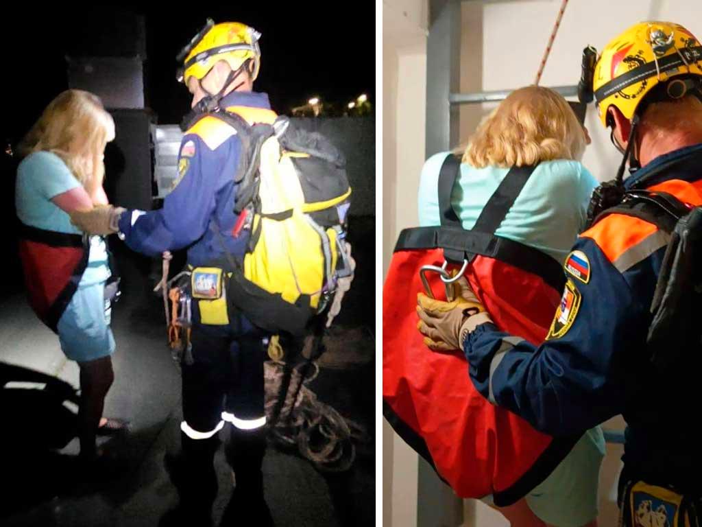 Женщина спасена спасателями после того, как застряла на крыше 13-этажного дома в поселке Дагомыс. Она не смогла спуститься самостоятельно и позвонила в службу спасения. Спасатели использовали альпинистское снаряжение, чтобы обеспечить ей безопасный спуск. После спасения женщина была передана медикам и полиции. На фото видно, как спасатели помогают ей спуститься. (Источник: sochinews.io)